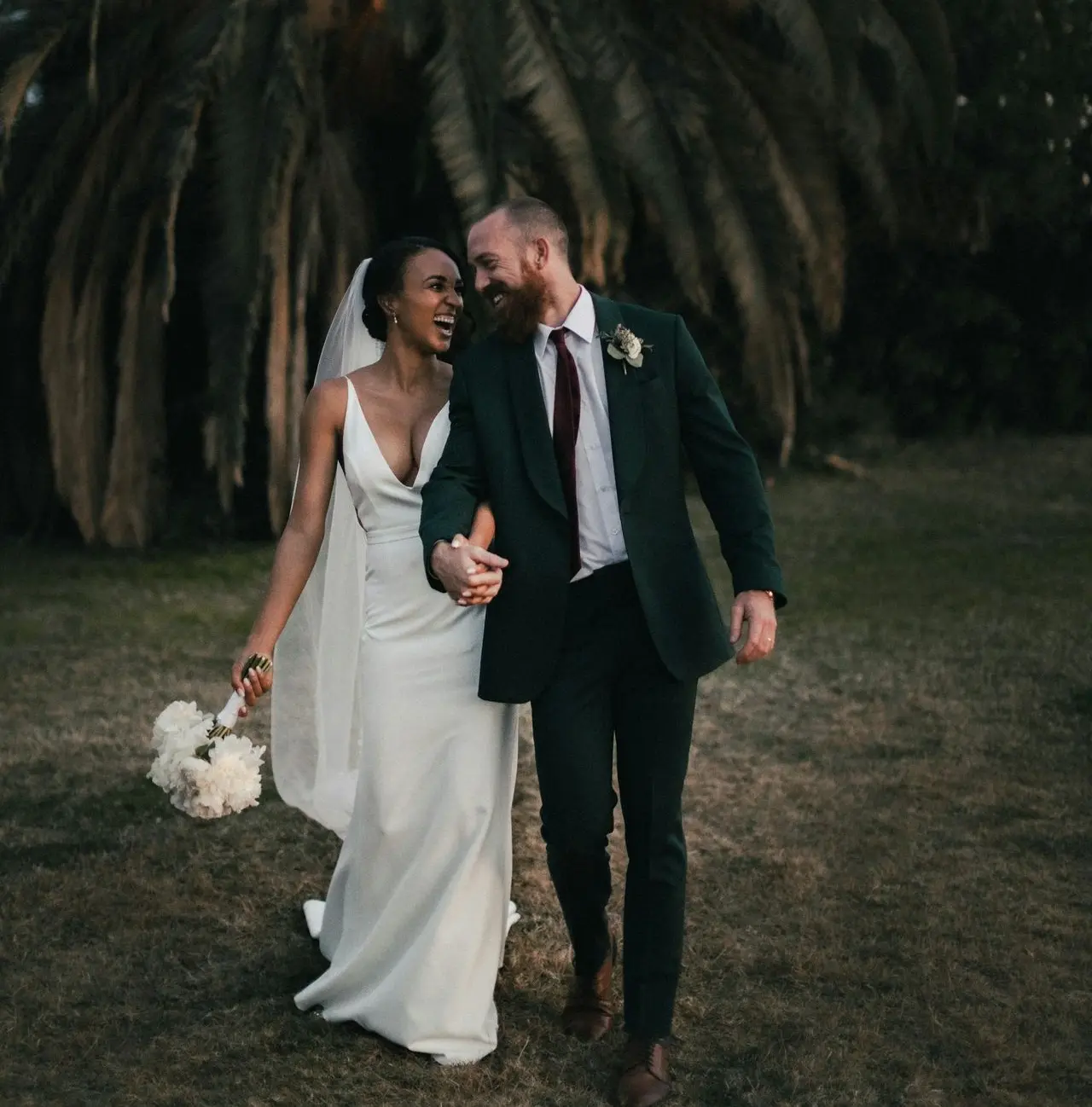 a newly married couple walking through a field